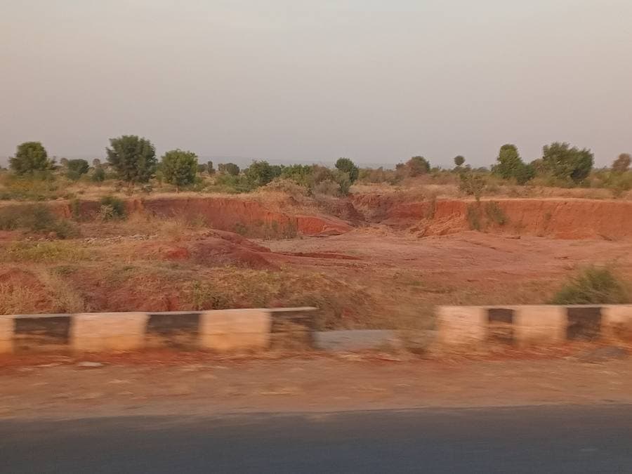 Cleared red-earth land beside a tarred road, northern Nigeria